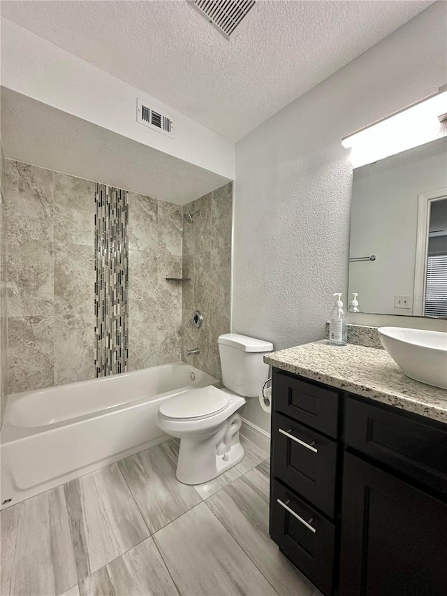 full bathroom with tiled shower / bath, vanity, toilet, and a textured ceiling