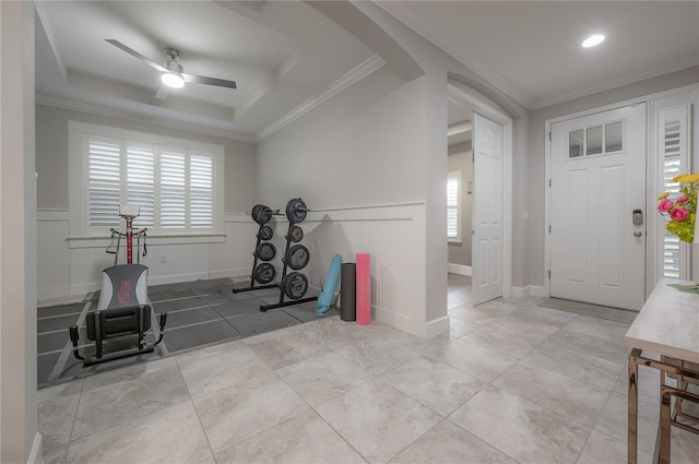 workout room featuring ornamental molding, plenty of natural light, ceiling fan, and a tray ceiling