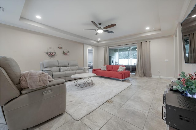 living room featuring ceiling fan and a tray ceiling