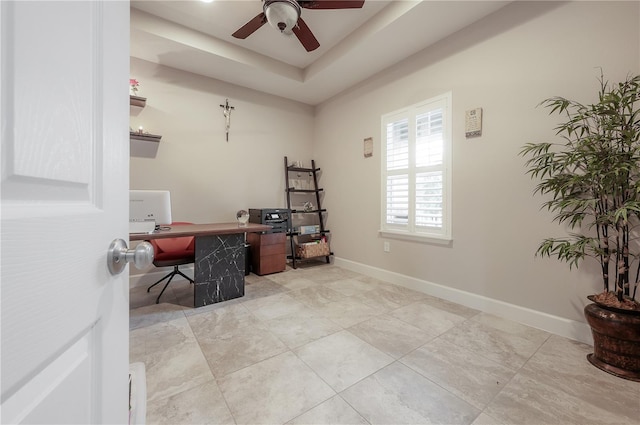 office area with a raised ceiling and ceiling fan