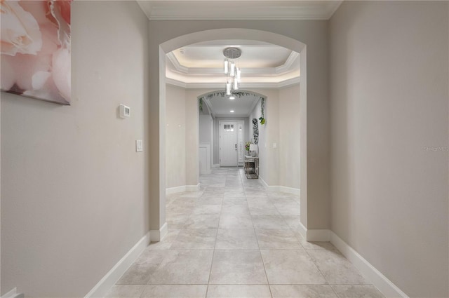 hall featuring a raised ceiling, crown molding, and light tile patterned floors