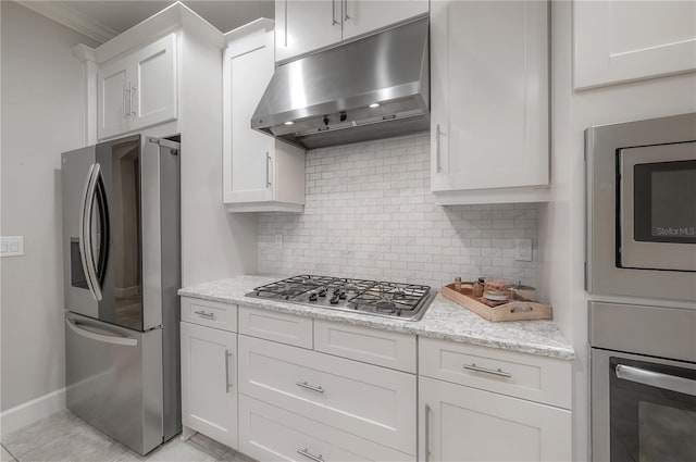 kitchen featuring crown molding, white cabinetry, stainless steel appliances, light stone counters, and decorative backsplash