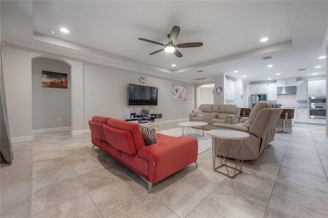 tiled living room featuring a raised ceiling and ceiling fan