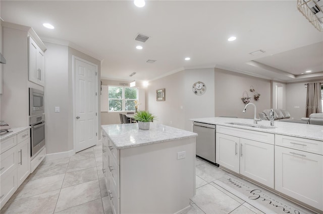 kitchen featuring appliances with stainless steel finishes, an island with sink, sink, and white cabinets