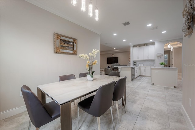 tiled dining room featuring sink and crown molding