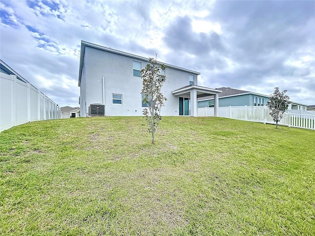 rear view of house featuring cooling unit and a yard