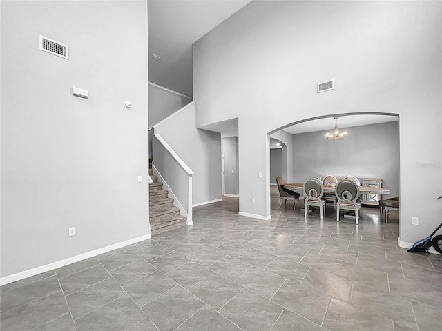 unfurnished dining area featuring baseboards, stairway, visible vents, and a notable chandelier