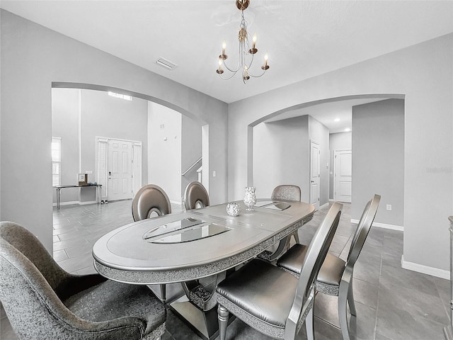 dining room featuring baseboards, visible vents, arched walkways, and a notable chandelier