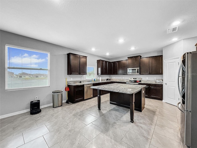 kitchen featuring stainless steel appliances, dark brown cabinets, a kitchen island, and visible vents