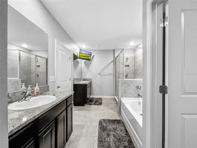 full bathroom with a stall shower, baseboards, two vanities, a sink, and a bath