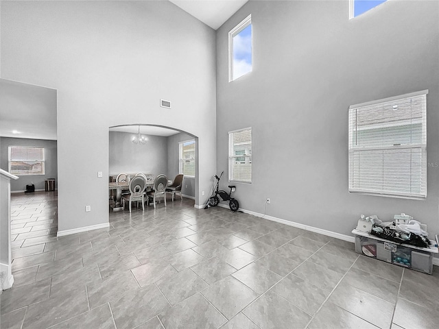 unfurnished living room featuring arched walkways, baseboards, visible vents, and a notable chandelier