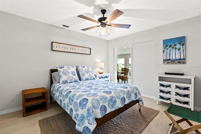 bedroom with a textured ceiling, ceiling fan, and light hardwood / wood-style floors