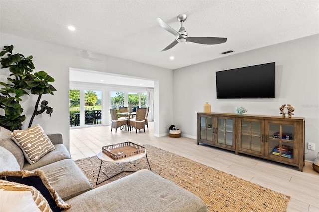 living room with a textured ceiling and ceiling fan