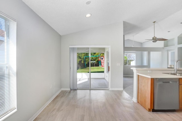 kitchen featuring a textured ceiling, stainless steel dishwasher, sink, and light hardwood / wood-style floors