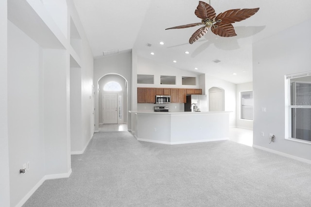 unfurnished living room featuring a ceiling fan, visible vents, high vaulted ceiling, arched walkways, and light carpet