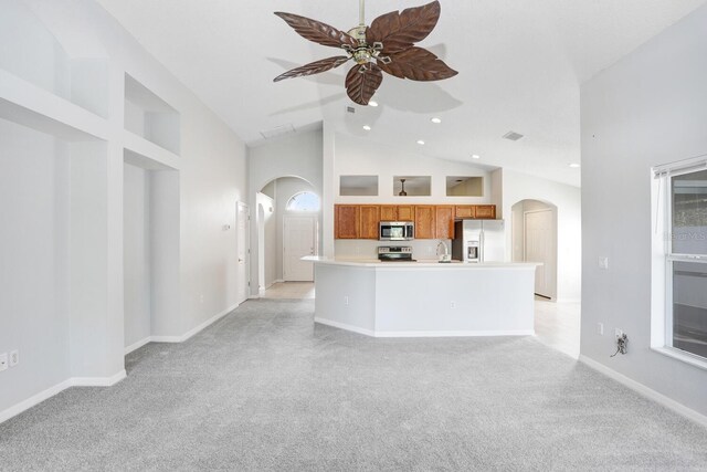 kitchen with ceiling fan, high vaulted ceiling, stainless steel appliances, and light colored carpet