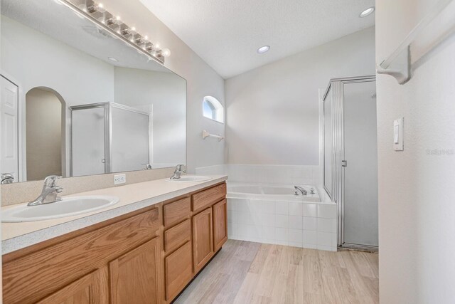 bathroom with lofted ceiling, vanity, independent shower and bath, and hardwood / wood-style flooring