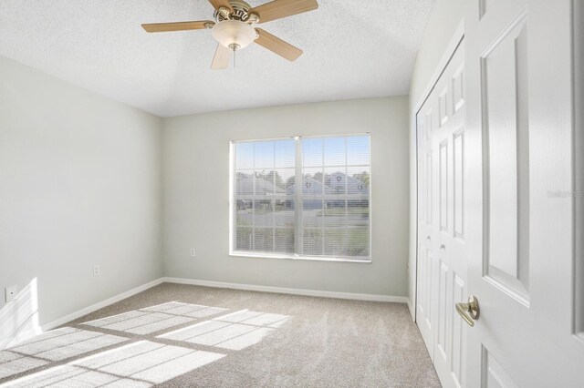 spare room featuring ceiling fan, light carpet, and a textured ceiling