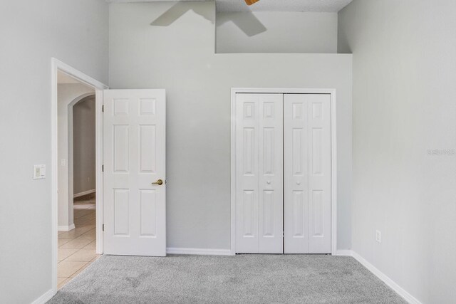 unfurnished bedroom with a closet, ceiling fan, and light carpet