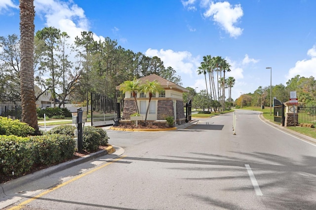 view of street featuring street lights, a gate, curbs, and a gated entry