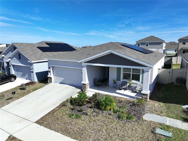 view of front of home with a garage, central AC unit, covered porch, and solar panels