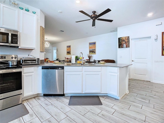 kitchen with sink, white cabinetry, kitchen peninsula, ceiling fan, and stainless steel appliances