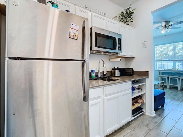 kitchen with white cabinetry, sink, stainless steel appliances, and ceiling fan