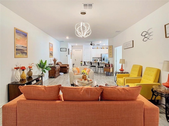 living room with ceiling fan with notable chandelier and light wood-type flooring