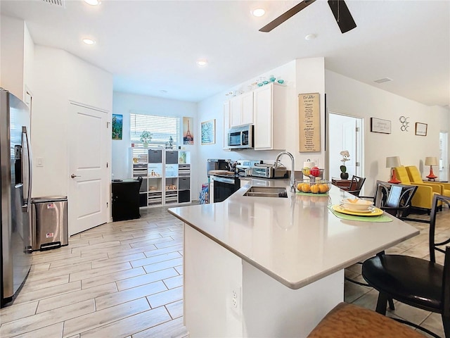 kitchen featuring sink, white cabinetry, a kitchen breakfast bar, ceiling fan, and stainless steel appliances