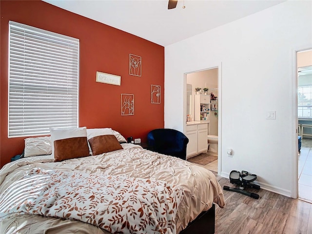 bedroom with connected bathroom, ceiling fan, and light hardwood / wood-style flooring