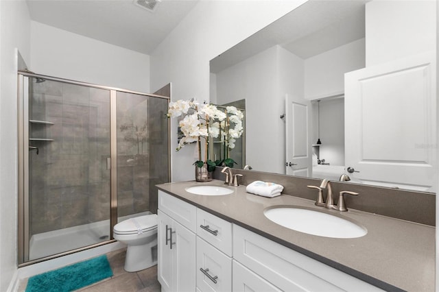 full bathroom featuring a stall shower, a sink, toilet, and double vanity