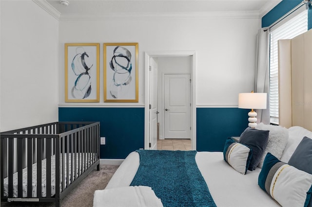 bedroom featuring ornamental molding, light carpet, and a crib