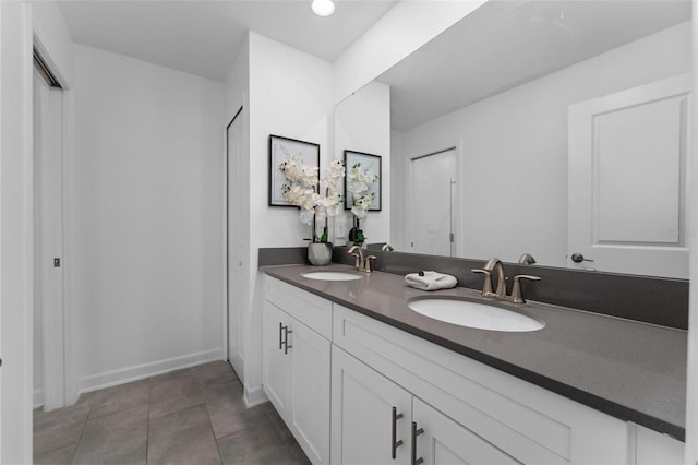 full bath with double vanity, a closet, a sink, and tile patterned floors