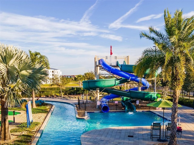 view of swimming pool featuring fence, playground community, a water slide, and a water play area