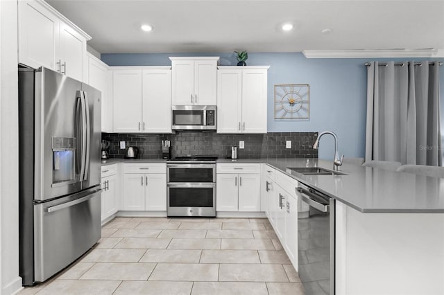 kitchen featuring kitchen peninsula, sink, appliances with stainless steel finishes, and white cabinets