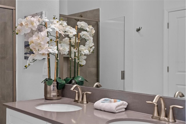 bathroom with double vanity, a shower stall, and a sink