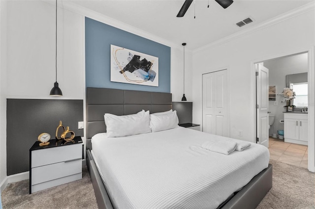 bedroom featuring ceiling fan, light colored carpet, visible vents, ornamental molding, and ensuite bath