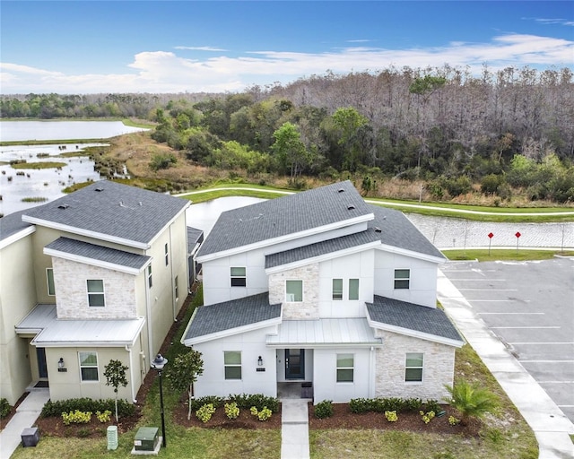 view of front of house with a water view, stone siding, metal roof, and roof with shingles