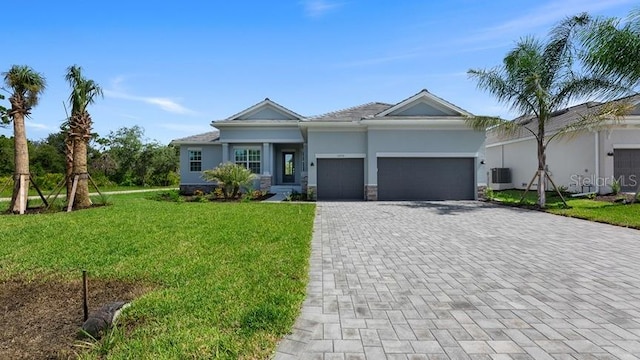 view of front of property featuring a front yard, an attached garage, central AC, stucco siding, and decorative driveway