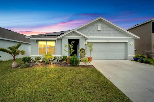 view of front of home featuring a garage, a yard, and solar panels