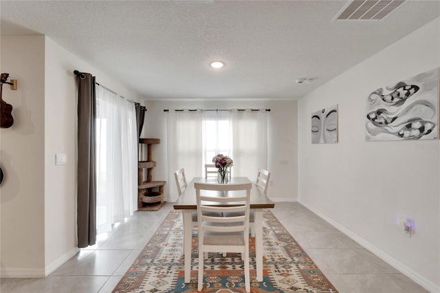 tiled dining space featuring a textured ceiling