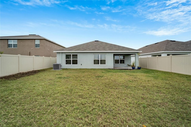 rear view of house with cooling unit and a yard