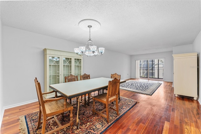 dining room featuring hardwood / wood-style flooring, a notable chandelier, and a textured ceiling