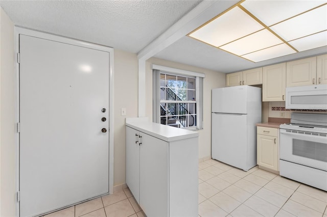 kitchen with a textured ceiling, cream cabinets, light tile patterned floors, and white appliances