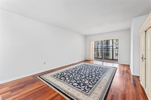 unfurnished room featuring a textured ceiling and dark hardwood / wood-style floors