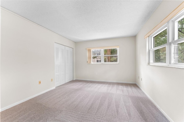 spare room featuring carpet, a healthy amount of sunlight, and a textured ceiling