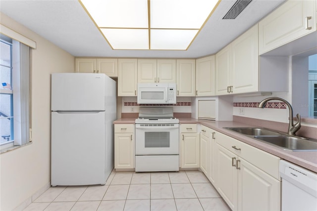 kitchen with light tile patterned flooring, white appliances, and sink