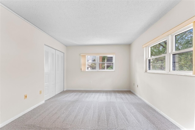 unfurnished room with light colored carpet and a textured ceiling