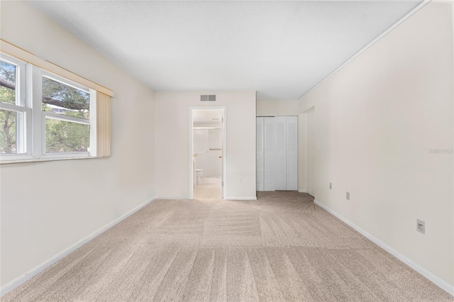 unfurnished bedroom with light carpet and connected bathroom