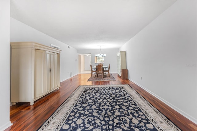 hallway featuring dark wood-type flooring and a notable chandelier